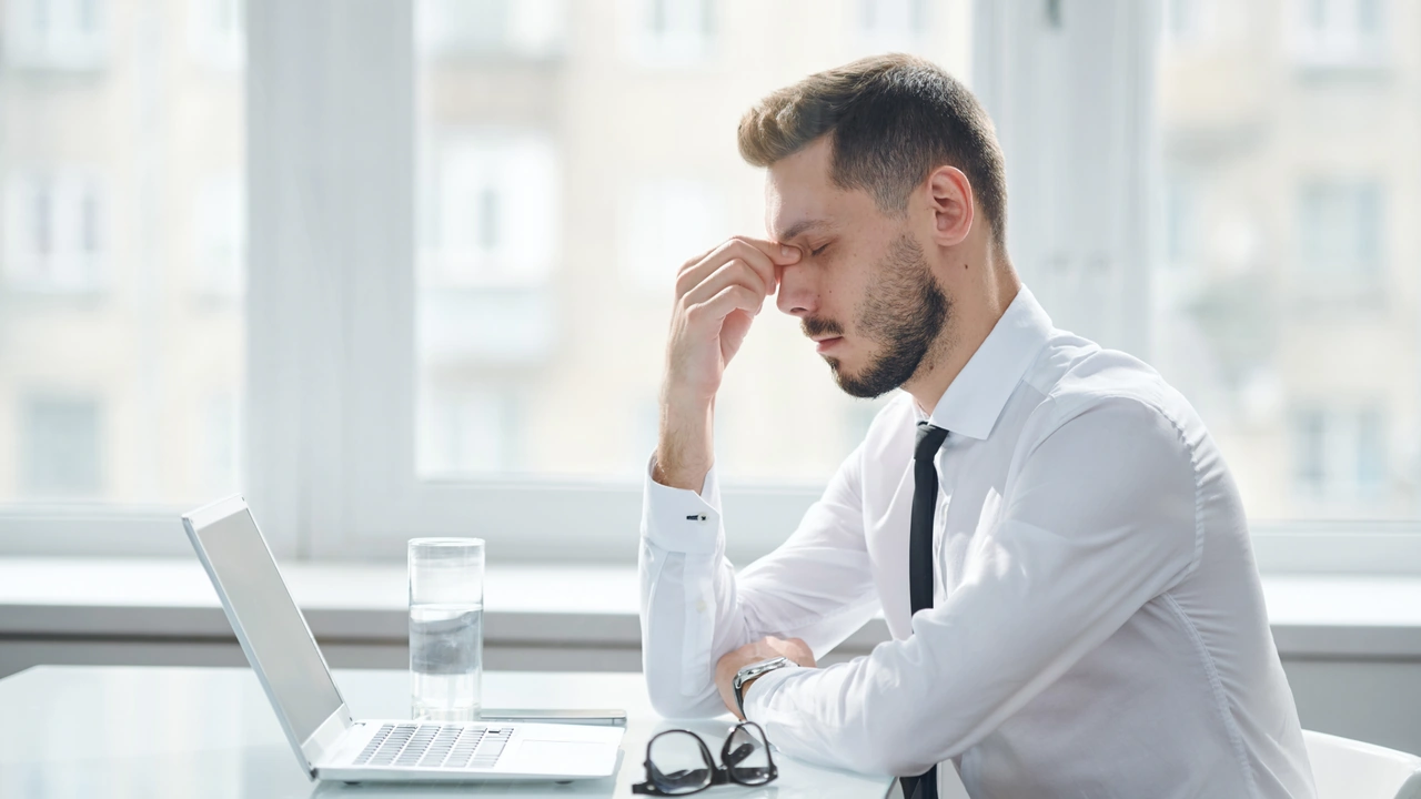 Homme fatigué devant son ordinateur, illustration du stress lié à l’environnement de travail